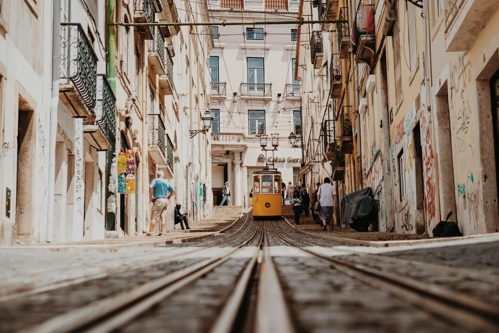 Yellow vintage tram climbing a steep cobbled street in Lisbon's Alfama district
