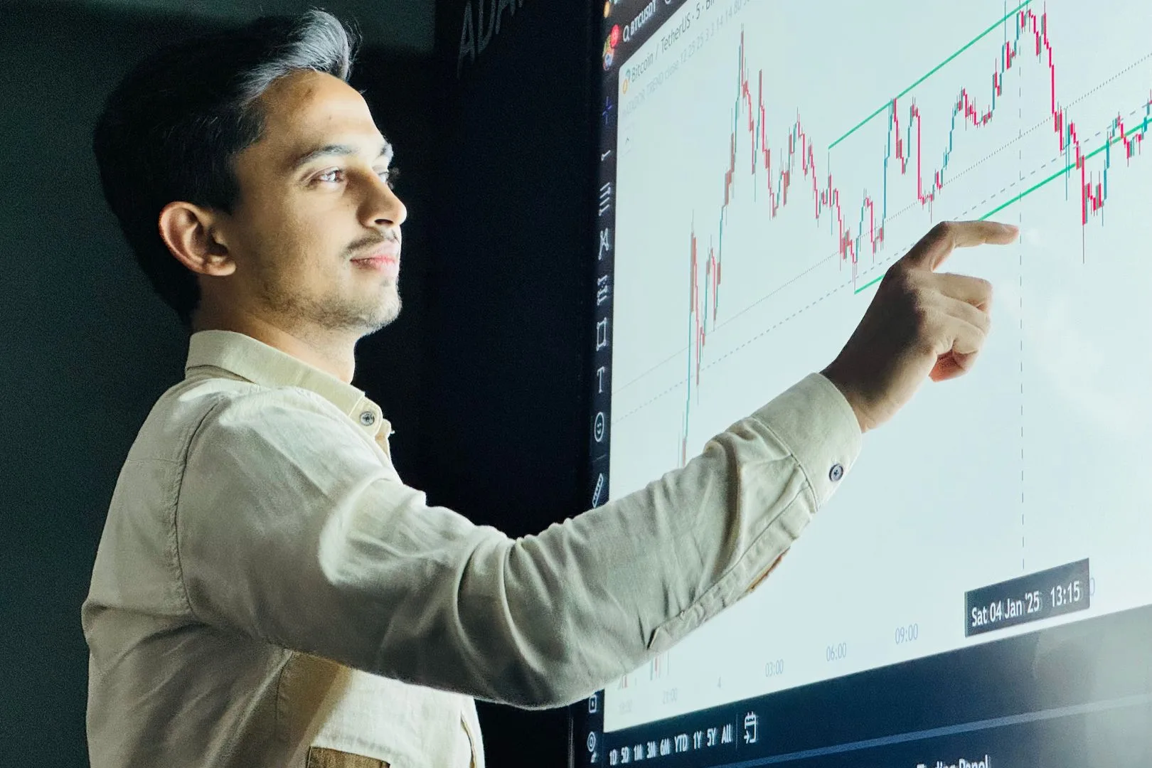 Man analyzing stock market graph on a digital board with a focused expression.